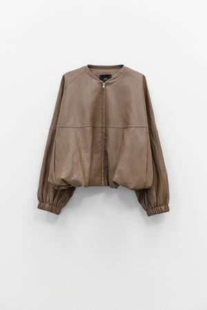The ELEH - THE MOD BOMBER JACKET by ELEH is a brown leather jacket featuring a sculptural design, front zipper, round neckline, and long oversized sleeves with gathered cuffs, shown against a plain white background.
