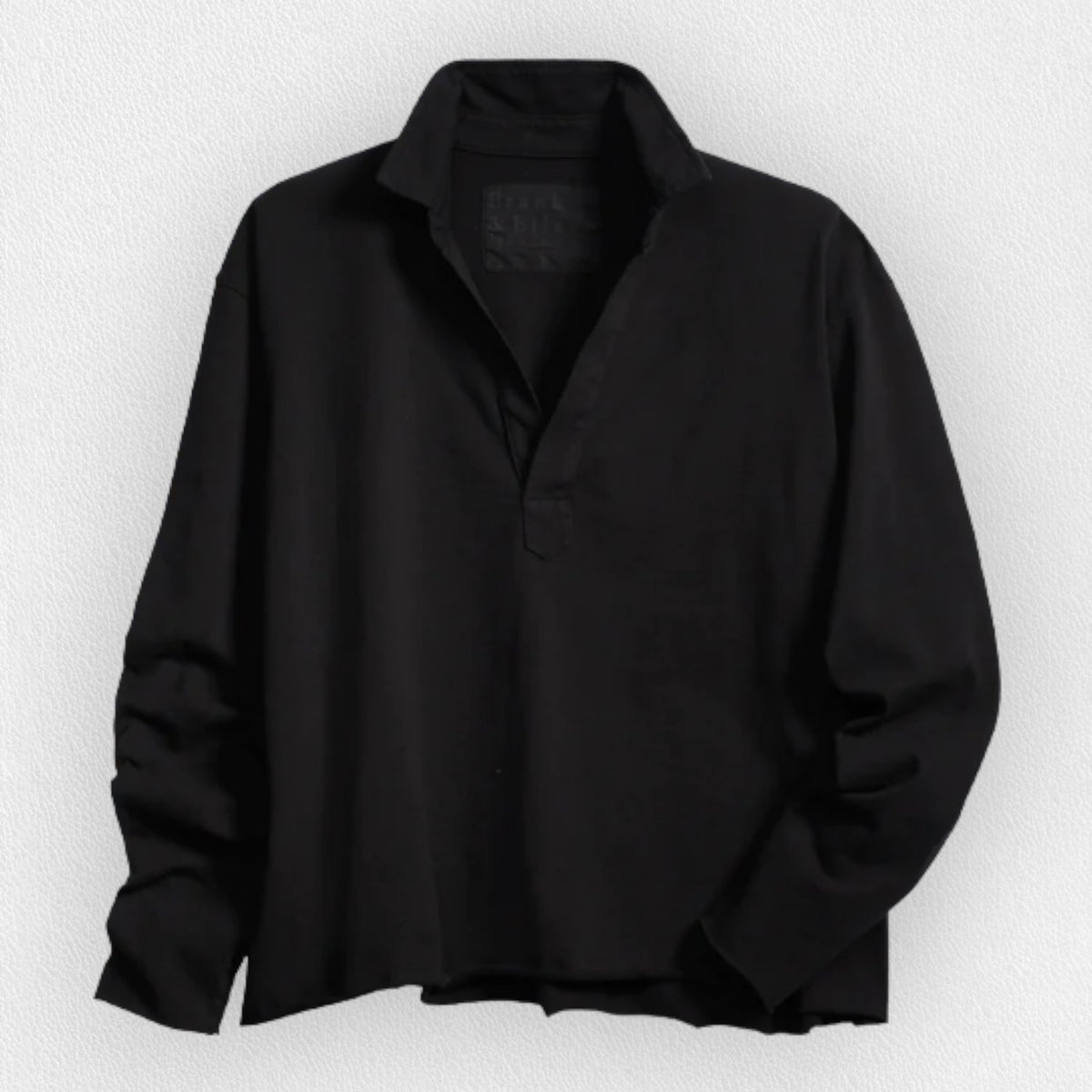 The FRANK &amp; EILEEN PATRICK POPOVER HENLEY in Heritage Jersey Black features a sporty V-neck with a collar and raw-cut hem, set against a light, textured background.