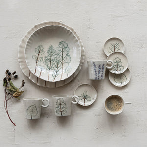 Two views of the CREATIVE COOP HAND-PAINTED ORGANIC SHAPED STONEWARE LOW BOWL WITH BOTANICALS: one features botanical artwork of trees inside, while the other shows its scalloped, organic-shaped edge.
