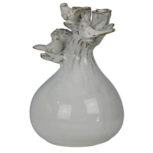 The HOMART CERAMIC VASE WITH BRANCH AND BIRD features white flowers and branches, set on a wooden surface with framed bird art and a woven basket against a light gray textured wall for a cozy touch.