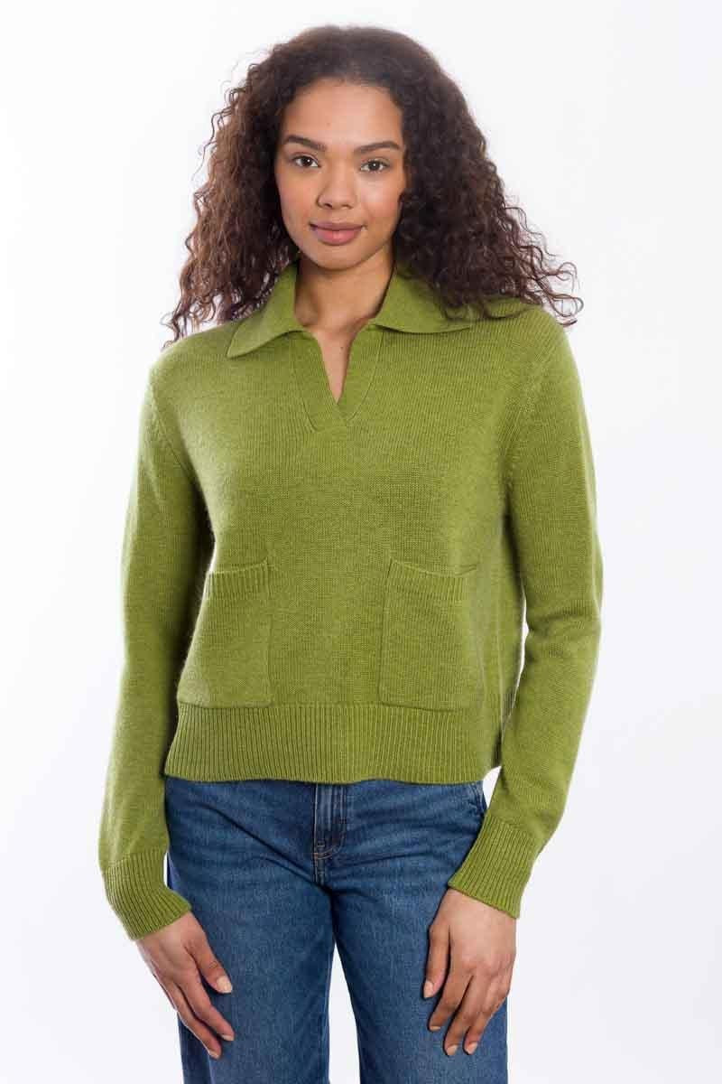 A woman with curly hair wears the & ISLA - Splitneck Pocket Polo in Moss by & ISLA, paired with blue jeans, standing against a plain white background.