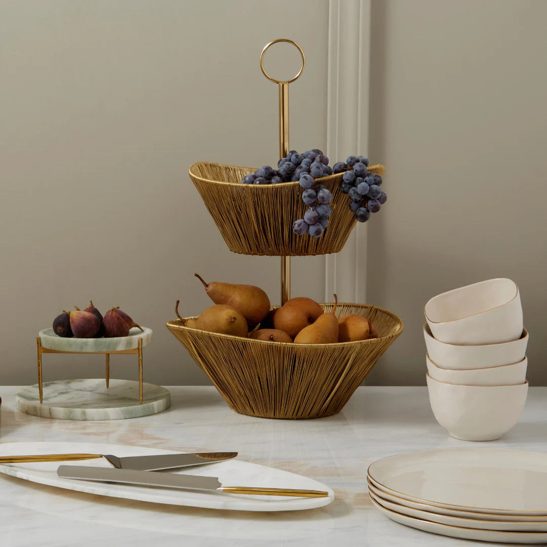 The SUN &amp; MOON CAKE LIFT SET by BE HOME, INC is elegantly displayed diagonally on a plain, light beige surface. The set includes a pie server with a wide, triangular blade and a cake knife featuring a long, narrow blade. Both pieces showcase a sleek, modern design and are handcrafted with a durable PVD finish.