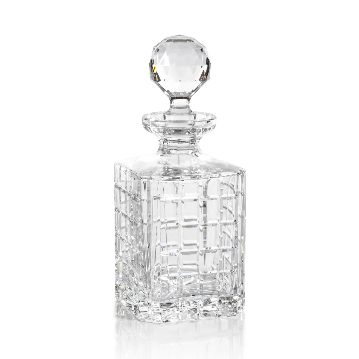 The BELMORE CRYSTAL GLASS WHISKEY & BRANDY DECANTER by ZODAX, featuring a faceted stopper and partially filled with whiskey, rests on a table beside matching barware—a glass and a pen.