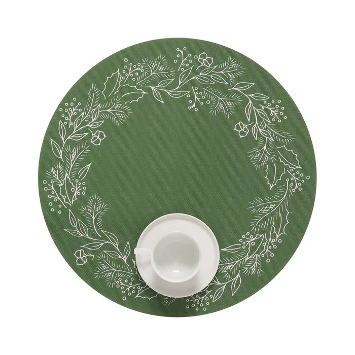 A slice of pie on a dark green plate with a fork rests on the CHILEWICH - WREATH PRINT PLACEMAT by CHILEWICH, featuring white botanical designs that add charm to the wooden table.