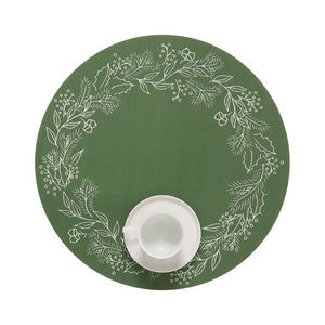 A slice of pie on a dark green plate with a fork rests on the CHILEWICH - WREATH PRINT PLACEMAT by CHILEWICH, featuring white botanical designs that add charm to the wooden table.
