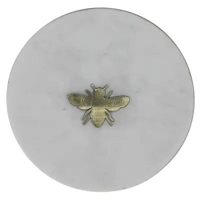 The HOMART MARBLE TRAY INLAID WITH BRASS BEE is a round, white marble tray featuring a small brass bee at the center and measures 6 inches in diameter.