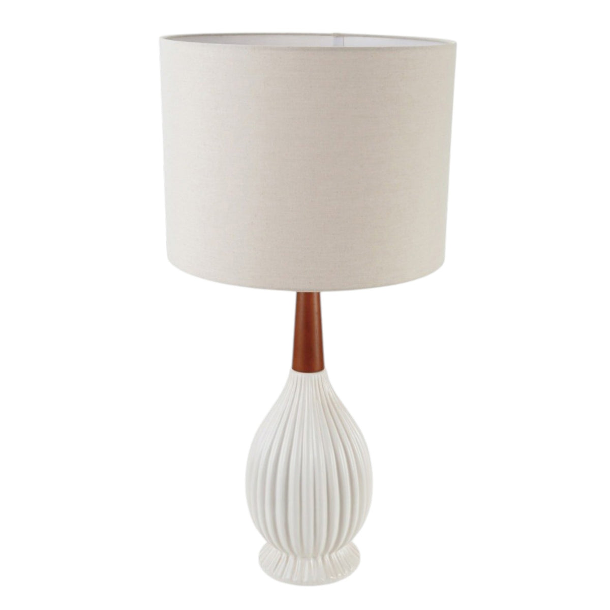 A cozy armchair with a black and white throw blanket sits by a marble side table holding wine. Nearby is the CREATIVE COOP PLEATED STONEWARE TABLE LAMP WITH RUBBERWOOD NECK AND LINEN SHADE, a potted plant, and a landscape painting on the wall.