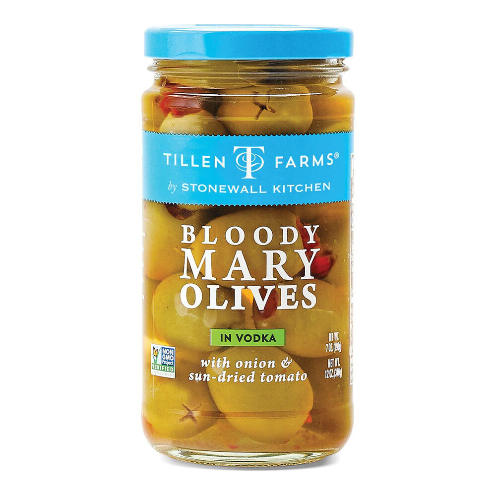 A glass jar with a blue lid contains STONEWALL KITCHEN-TF BLOODY MARY OLIVES by STONEWALL KITCHEN. These premium green olives are immersed in vodka, complemented by onion and sun-dried tomato. Perfect as a savory cocktail snack or Bloody Mary garnish, the jar also features the Non-GMO Project Verified logo.