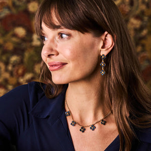 The CAPUCINE DE WULF Berry Clover Multi Station Necklace features five evenly spaced clover-shaped pendants set with labradorite. Finished in 18K gold, it includes an adjustable clasp and a decorative gold charm for a refined look.