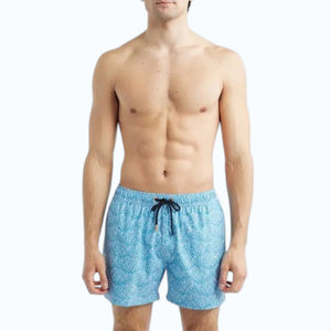 A shirtless man wears SAVE THE DUCK - ADEMIR swim trunks in light blue corals NO FISHING, made from quick-dry recycled polyester with a black drawstring, standing against a plain white background.