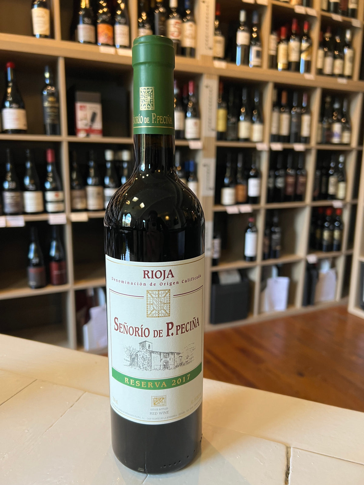 A bottle of PECINA RIOJA RESERVA 2017 by WINE: ADVINTAGE with a cream and green vineyard-illustrated label, shown on a plain white background.
