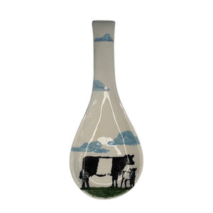 The FEARRINGTON SIGNATURE COLLECTION - BELTIE SPOON REST BY VIETRI features a playful black and white Beltie cow design with a UFO beam—an eye-catching, quirky accent from VIETRI that brings Fearrington Village charm to your kitchen.