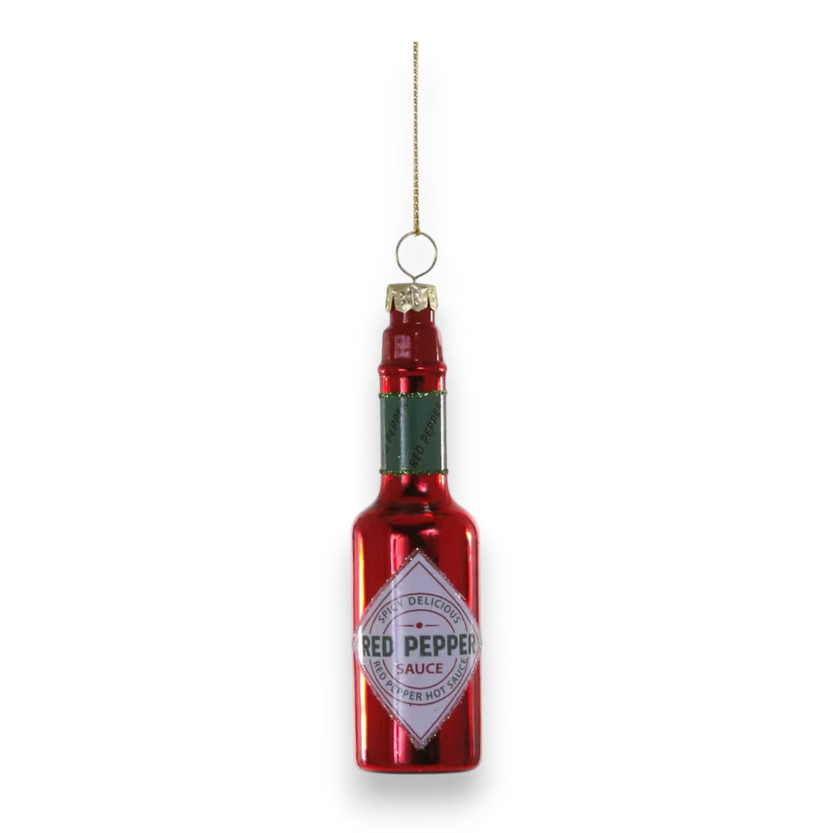 The CODY FOSTER HOT SAUCE ORNAMENT is a shiny red glass decoration (1x1x4) shaped like a hot sauce bottle, with a green neck, gold hanging string, and a white label that says “Red Pepper Sauce.”.