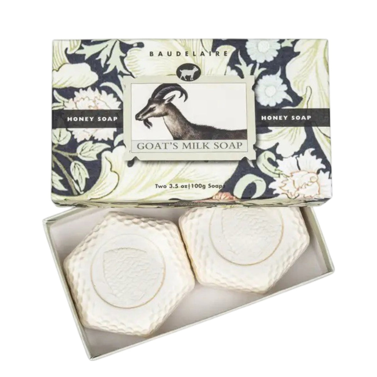 An open BAUDELAIRE - GOATS MILK HONEY SOAP 3.5oz 2 Bar Gift Box displays two hexagonal white soaps, ideal for sensitive skin. The cream and black box features a decorative floral print and an illustration of a goat.
