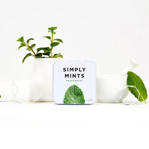 A small white tin labeled "SIMPLY GUM - PEPPERMINT MINTS" with a large image of a green peppermint leaf below the text. Experience a burst of freshness with these peppermint mints from SIMPLY GUM. The net weight is indicated as 1.1 oz (30g) in the bottom right corner.