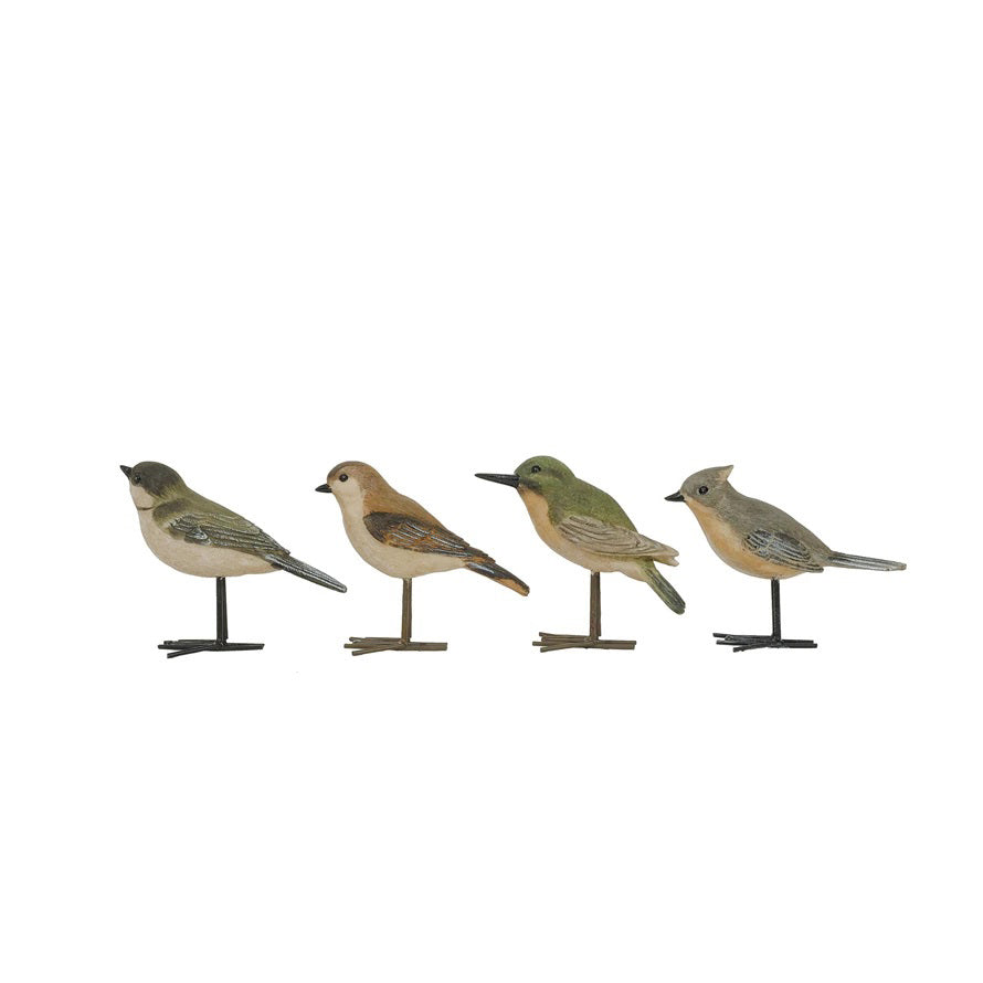 Four small, realistic CREATIVE COOP resin bird figurines from the BIRD WITH METAL FEET range, each uniquely colored and marked, stand on simple metal feet in a row against a plain white background.