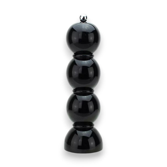 A vibrant display of ADDISON ROSS LONDON - BOBBIN SALT OR PEPPER MILL 24CM grinders in various shades such as pink, red, blue, orange, yellow, green, white, and a striking black lacquered finish. They are arranged on two shelves against a muted green background alongside various serving bowls.