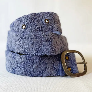 The JENNY KRAUSS - AZURE SEAS EMBROIDERED WOOL BELT by JENNY KRAUSS features an embroidered floral pattern, an adjustable waist, and a silver rectangular buckle, shown coiled on a white surface.