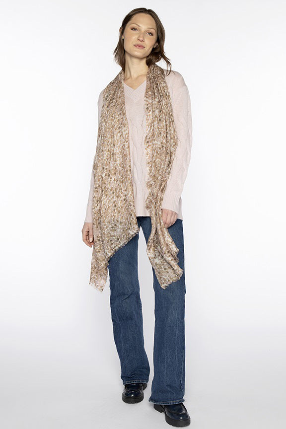 A woman poses against a white background wearing a light pink sweater, blue jeans, black shoes, and the KINROSS CASHMERE - PEBBLE PRINT SCARF by KINROSS in a silk cashmere blend draped over her shoulders.