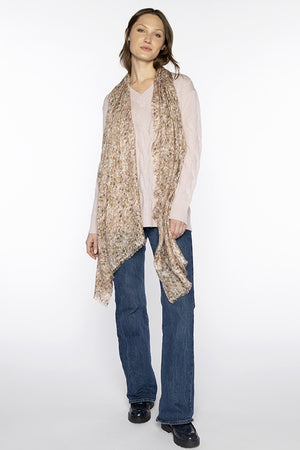 A woman poses against a white background wearing a light pink sweater, blue jeans, black shoes, and the KINROSS CASHMERE - PEBBLE PRINT SCARF by KINROSS in a silk cashmere blend draped over her shoulders.