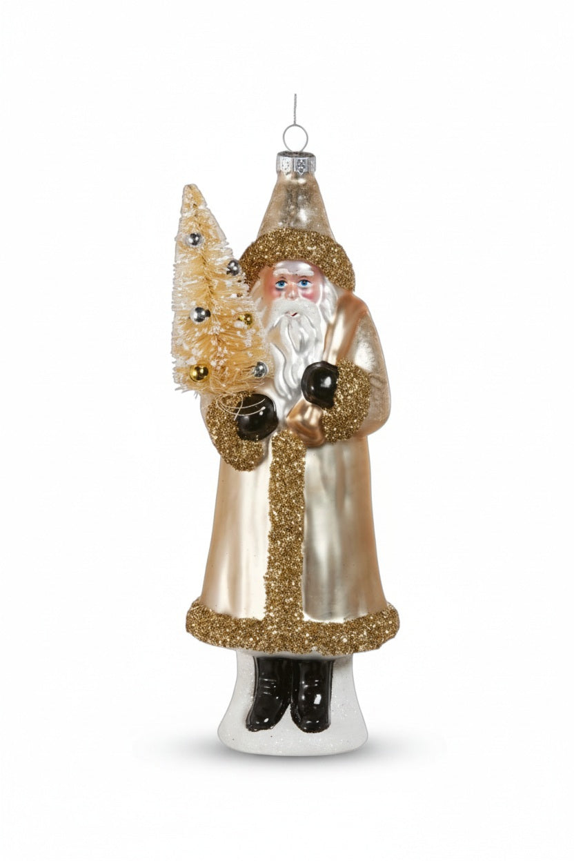 GLASS GLITTER SANTA ORNAMENT in a cream-colored coat with gold glitter trim, carrying a small decorated bottle brush tree, perfect for adding to glass decor collections.
