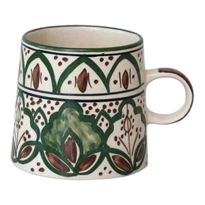 The CREATIVE COOP HAND-PAINTED STONEWARE MUG features a green and brown floral pattern and measures 3.5 inches high by 3.75 inches wide, as illustrated with measurement indicators.
