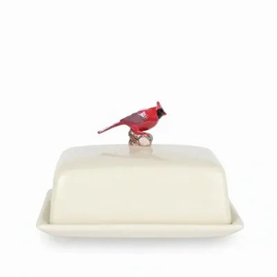 The QUAIL CERAMICS - CARDINAL BUTTER DISH by QUAIL DESIGNS is a white ceramic butter dish with a lid featuring a hand painted red cardinal figurine handle. Set against a white background, this dishwasher safe dish is both charming and practical.