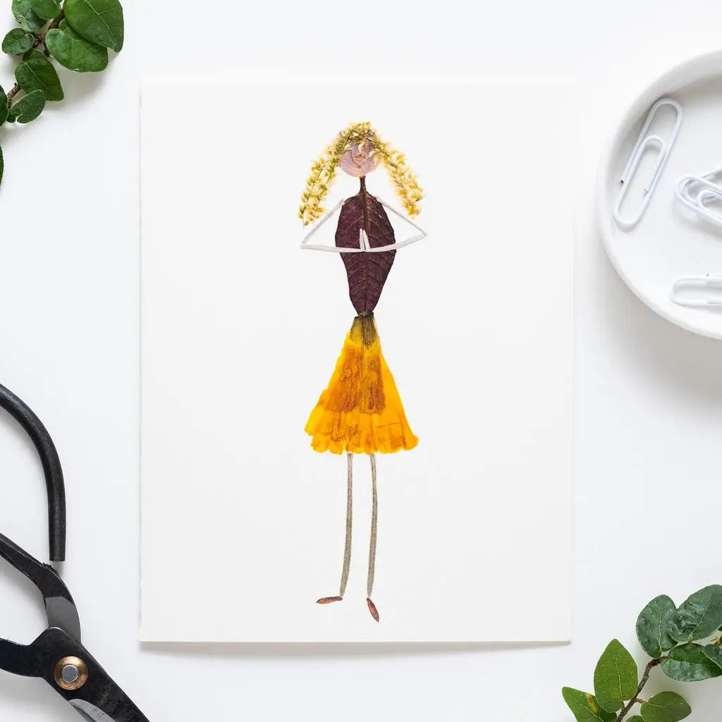 The PETAL PEOPLE PRESS - GRATITUDE CARD features a creative drawing of a girl made from dried leaves and petals on white paper, styled as botanical art, and shown on a white table with paper clips, a black tool, and green leaves.