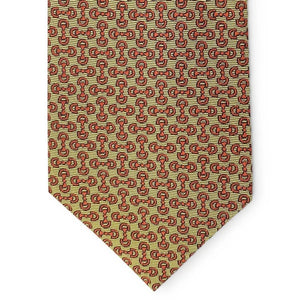 A close-up of the BIRD DOG BAY PETER-BLAIR - HORSEBIT SILK TIE IN YELLOW, featuring a handmade New York woven silk construction with a repeating pattern of small red horseshoes and horse heads on a yellow background. The tie has a pointed tip at the bottom.