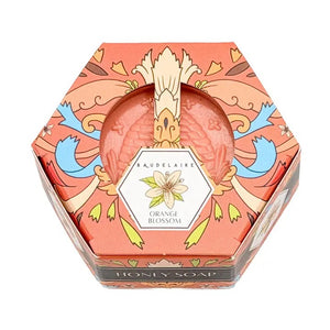 A hexagonal box of BAUDELAIRE - ORANGE BLOSSOM HONEY SOAP 3.5 OZ features a top panel displaying product benefits, a list of available scents—including Goat Milk Soap, Honey Soap, Royal Jelly, Lavender, Calendula, Pure Honey, and Orange Blossom—along with the ingredient list, barcode, and “Made in the USA” branding.