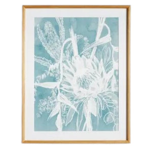 A framed protea abstract print in soft blue by NAPA HOME AND GARDEN, featuring a white floral illustration on a blue background. This botanical wall art is presented in a light wood frame for a fresh, contemporary look—perfect for modern home décor.