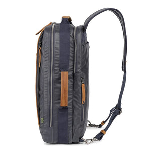 The TSD BRAND - MADRONE COATED CANVAS BACKPACK IN NAVY features brown leather accents, a spacious main compartment, a padded laptop sleeve with snap closure, and multiple zippered pockets on the inside flap.