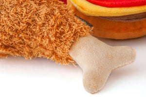 The AMERICAN CLASSIC FRIED CHICKEN dog toy by PLAY PET LIFESTYLES/BRANDS is a plush toy shaped like a fried chicken drumstick, featuring a textured orange-brown “meat” section and a smooth beige “bone” end.