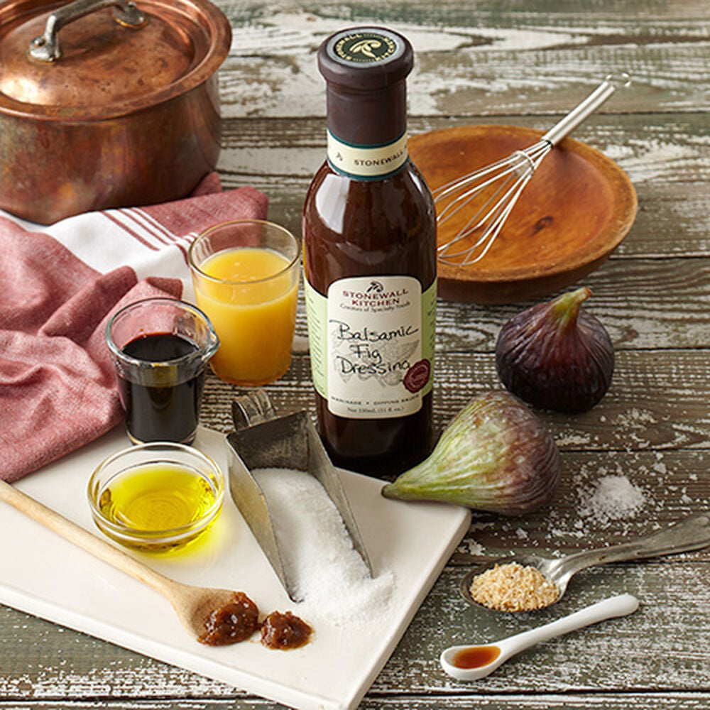 A bottle of STONEWALL KITCHEN-BALSAMIC FIG DRESSING features the product name on a dark bottle with a green label. This delicious gluten-free and non-GMO salad dressing comes in an 11 fl. oz (330 ml) size.