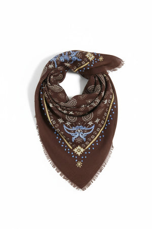 The STORIATIPIC - NELLY wool bandana scarf with embroidery in chocolate is crafted from a soft cashmere blend and features blue, yellow, and beige paisley and geometric patterns with frayed edges. Displayed folded in a triangle shape against a plain white background, this accessory highlights the distinctive style of the STORIATIPIC brand.