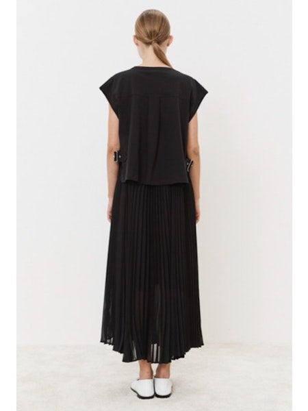 Against a plain white backdrop, a person models the MEIMEIJ Navy Plisse Dress. Paired with white pointed shoes, this minimalistic ensemble epitomizes versatile style. Their expression is neutral, enhancing the understated elegance of the look.