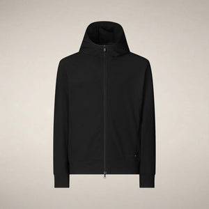 A man faces forward in the SAVE THE DUCK - LUIZ Hooded Jacket in Blue Black from SAVE THE DUCK, paired with black pants and white sneakers, set against a plain beige background.