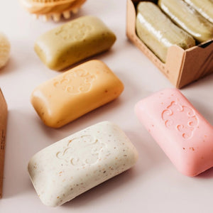 The BAUDELAIRE Grapefruit Loofa Bath Soap (5oz) is a pink rectangular bar featuring exfoliating seaweed, small brown specks, and a decorative swirl pattern embossed in the center. It offers a natural citrus fragrance that invigorates your senses.