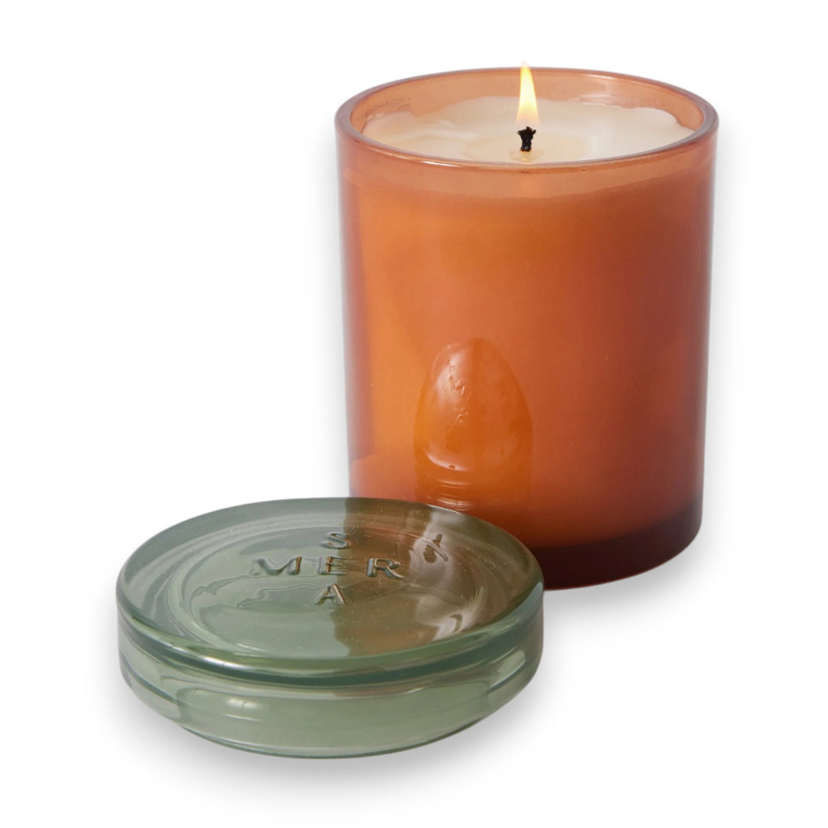 The MERSEA - BEACH BUNGALOW JOLIE JAR CANDLE by MERSEA is a burnt orange soy wax candle in a glass jar with a clear lid, photographed at an angle against a white background, evoking hints of eucalyptus and moss.