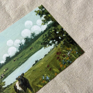 Bring the countryside to your home with the SOPHIE WYATT STUDIO - WILD MEADOWS & BELTIES ART PRINT (12x16). This fine art print by SOPHIE WYATT STUDIO depicts a serene scene where a Belted Galloway cow stands amid wildflowers beside a tranquil pond, while more cows graze in the distant field. Lush bushes frame the landscape and white fluffy clouds float across a vivid blue sky, perfectly capturing the peaceful charm of rural life.