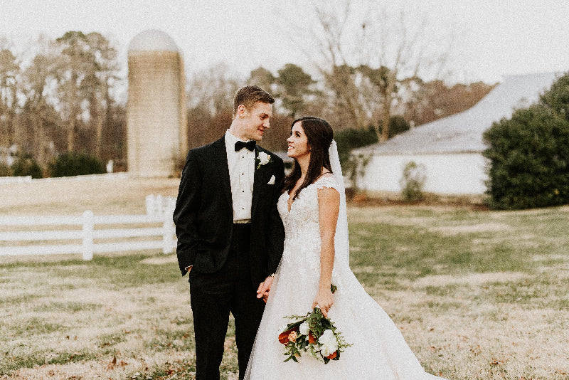 Wedding couple standing in a field with a barn in the background