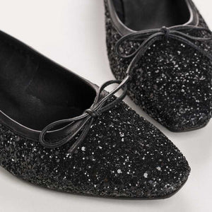 A single REQINS - FETICHE GLITTER HEELED BALLERINA shoe, black and covered in glitter, viewed from above with a small bow on the toe and "REQINS" on the insole—perfect elegant party shoes.