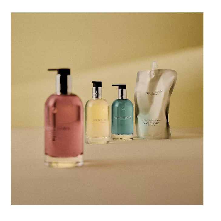 A clear bottle of MOLTON BROWN - GINGERLILY HAND WASH with a silver collar, pump dispenser, and pink soap is shown on a white background.