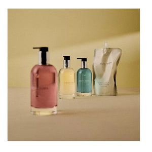 A clear bottle of MOLTON BROWN - GINGERLILY HAND WASH with a silver collar, pump dispenser, and pink soap is shown on a white background.