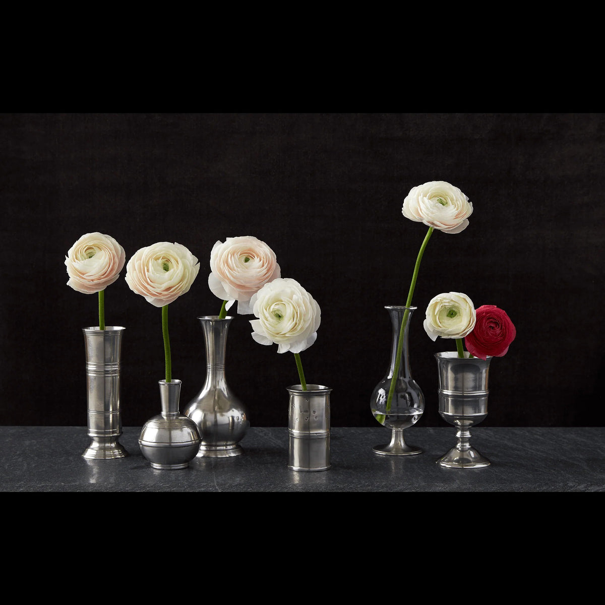 The MATCH - PEWTER BUD VASE by MATCH is a silver, round-bottomed vase with a narrow cylindrical neck, wide body, engraved lines, and dotted patterns around its midsection and shoulder, shown against a white background.