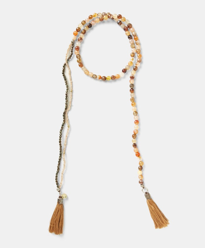 The MOMONI - NOEL NECKLACE by MOMONI features colorful round glass beads and two brown cotton tassels at each end, shown against a white background.