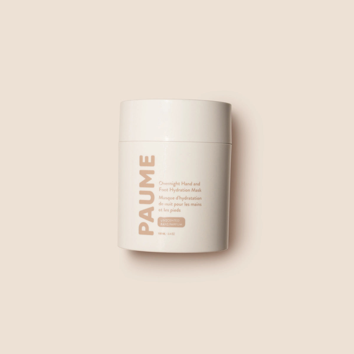 A white cylindrical container of PAUME’s OVERNIGHT HAND AND FOOT HYDRATION MASK rests on a creamy textured surface, with nourishing mask—ideal for dry, cracked skin—smeared around it.