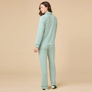 A woman wears the SOFTIES ARIA SLIM NOTCH COLLAR PJ SET, featuring a long-sleeved button-down top and matching wide-leg pants in red and white vertical stripes with red piping details.