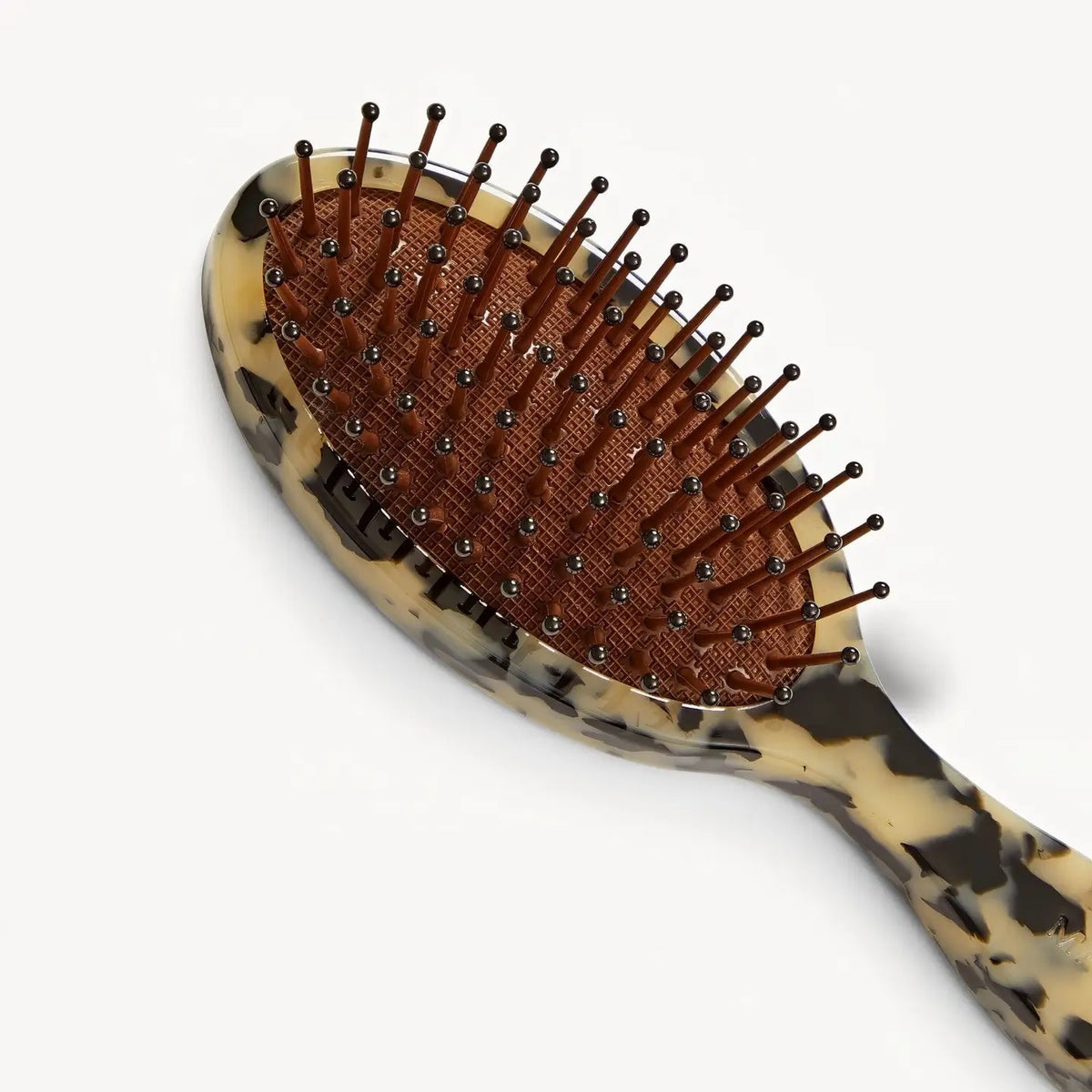 The MACHETE Petite Travel Detangling Hair Brush in Blonde Tortoise features nylon bristles on a brown cushioned pad and a marbled beige-and-black Italian acetate handle—ideal as a compact travel brush.