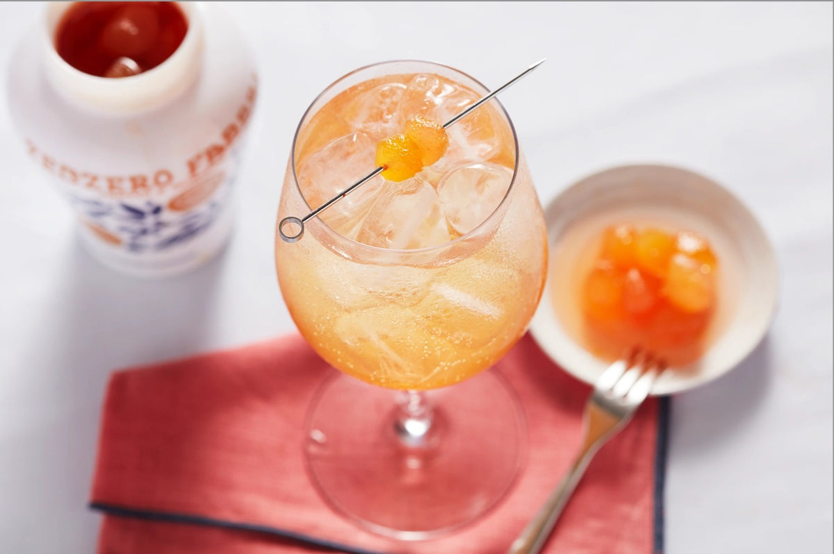 A vibrant jar of FABBRI - CANDIED GINGER IN SYRUP by Gourmet Food Solutions, featuring a decorative blue and white lid and an intricate orange and blue design on the glass. The front label prominently displays &quot;Gluten Free.&quot; The jar is set against a white background, capturing the essence of candied ginger.
